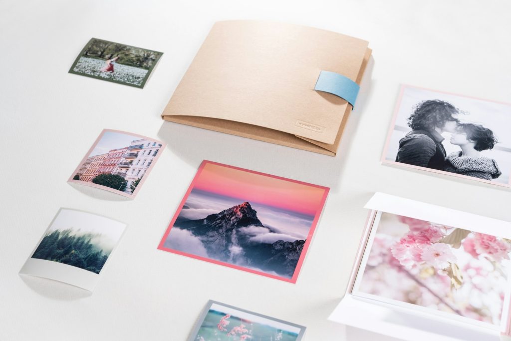Stampa Professionale Album and various printed photos laid out on a light background.