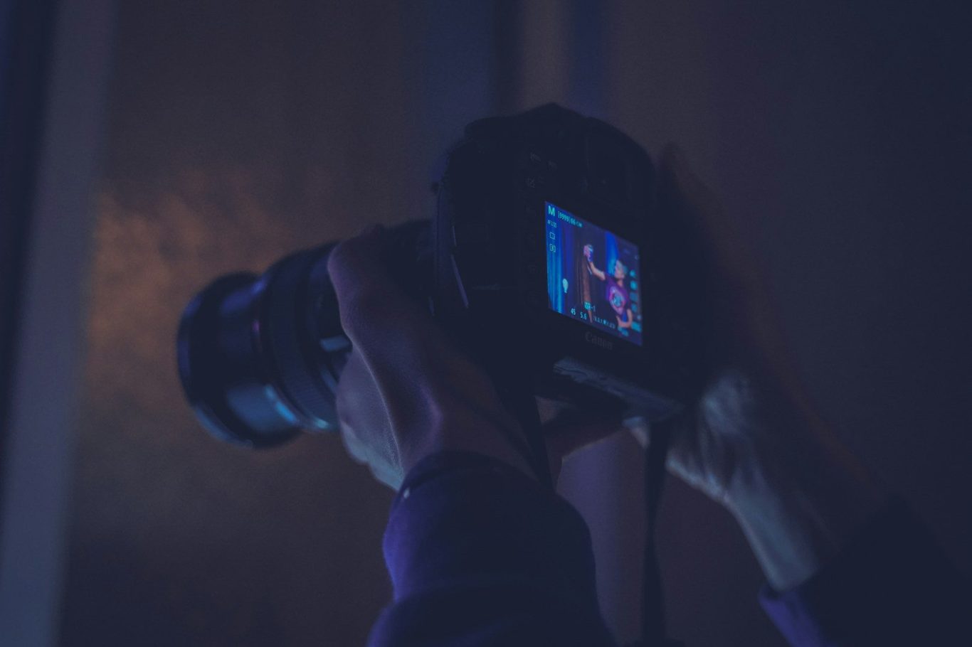 Riproduzioni Opere D'Arte Man holding a camera with a brightly lit screen displaying an image.