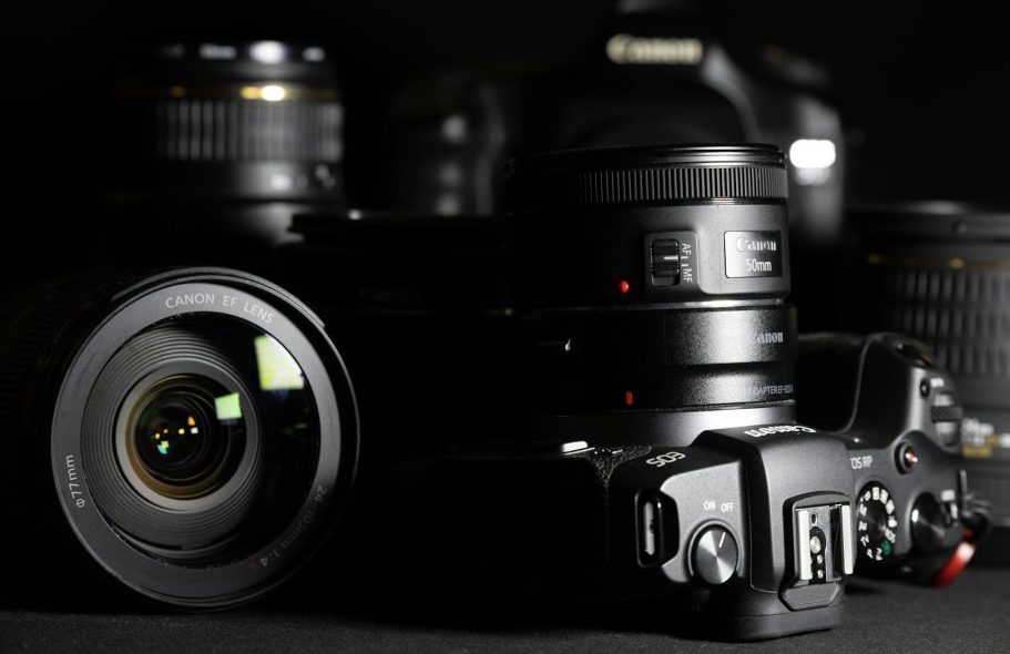 Various camera lenses and a camera body on a dark background.
