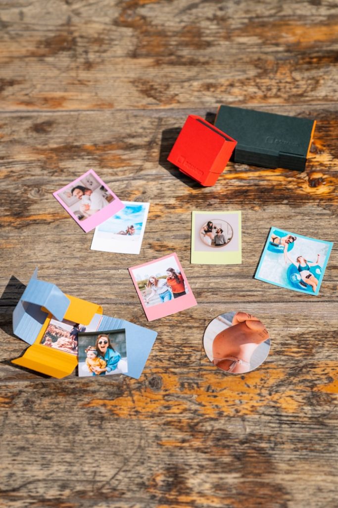 Stampa Digitale Stickers and small photos arranged on a wooden surface with colorful blocks.